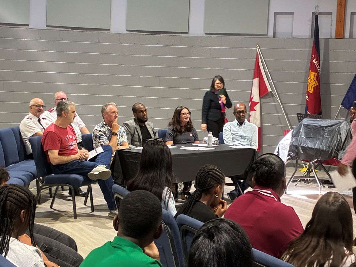 A panel of 5 judges listen intently to students presenting their business plan